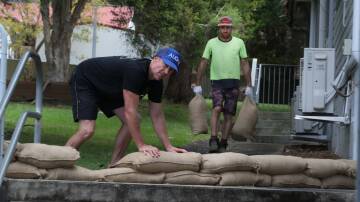 Mount Ousley Public School parents Joel Scott and Luke Smith placing sandbags to help protect the school during predicted wet weather this weekend. Picture by Robert Peet
